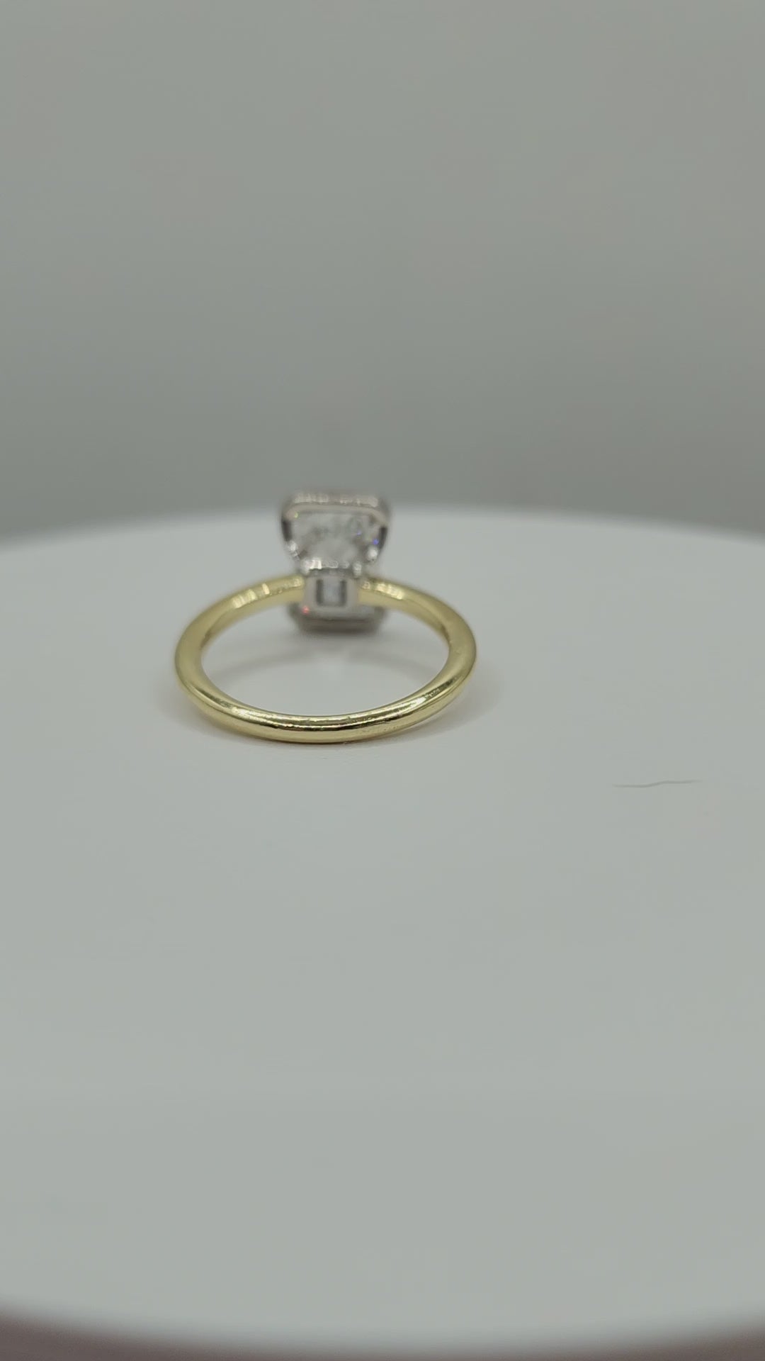 Gold ring spinning on a white display against a grey background