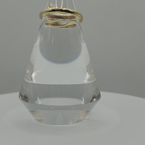 Diamond and yellow gold ring on a clear ring holder spinning on a display