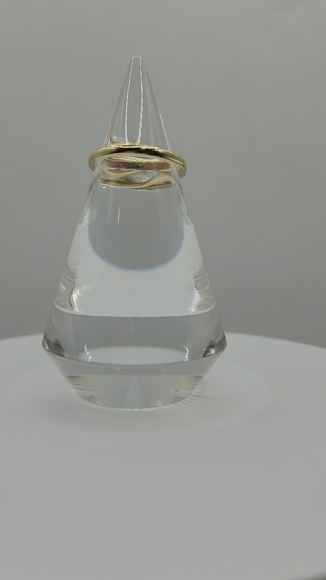 Diamond and yellow gold ring on a clear ring holder spinning on a display