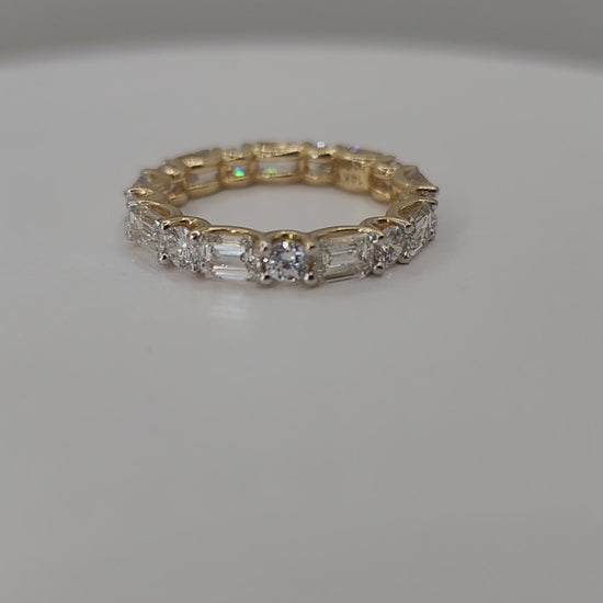 Yellow Gold ring with diamonds on a finger against a white background