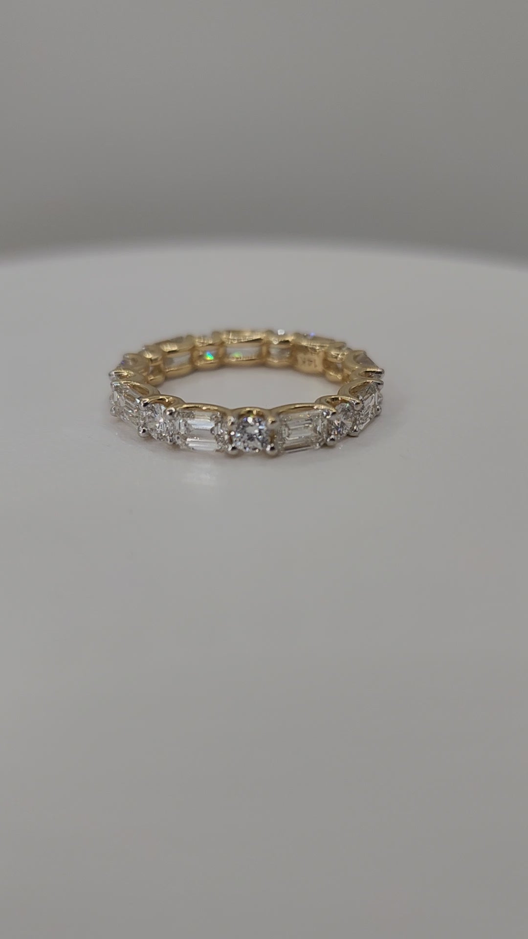 Yellow Gold ring with diamonds on a finger against a white background