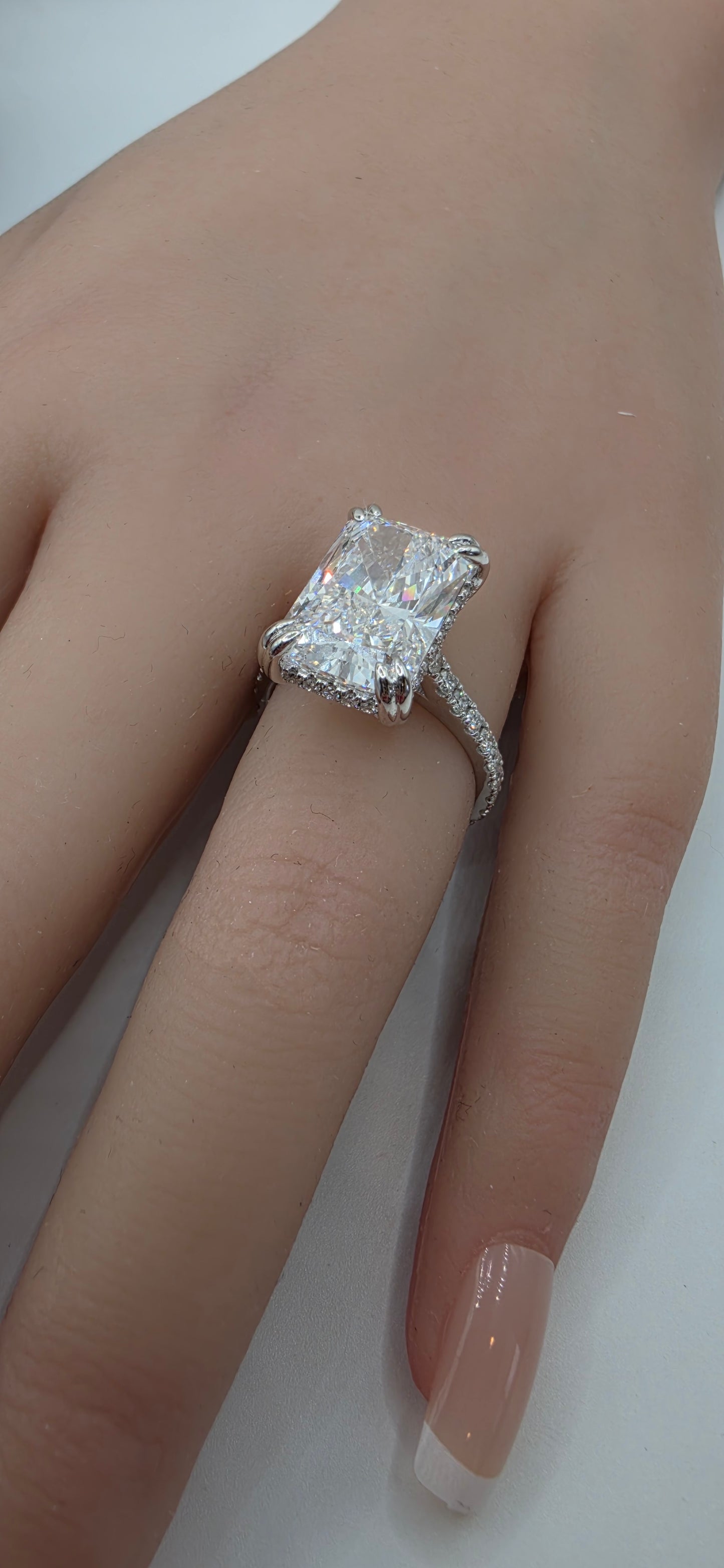 Close-up of a hand wearing a diamond ring on a plain background