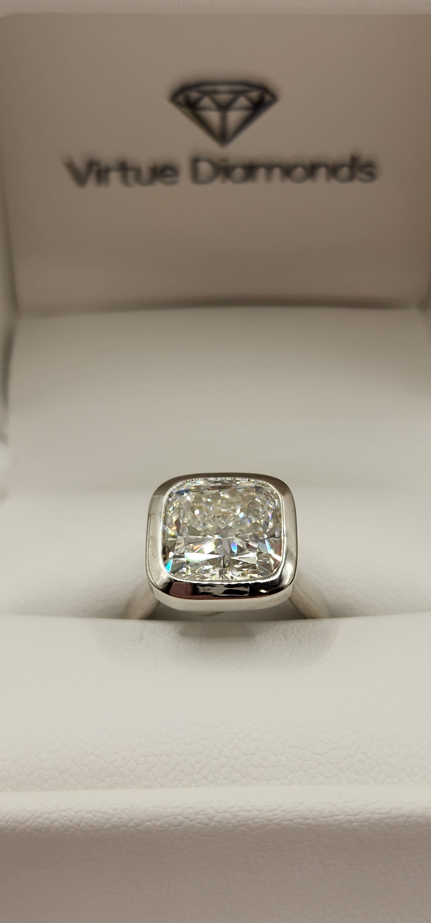 "The Brittney" is a 5.5 Carat Cushion Cut Lab Grown Diamond F/VS1, in a 14k White Gold Full Bezel, Cathedral Setting with Cross Cross Prongs