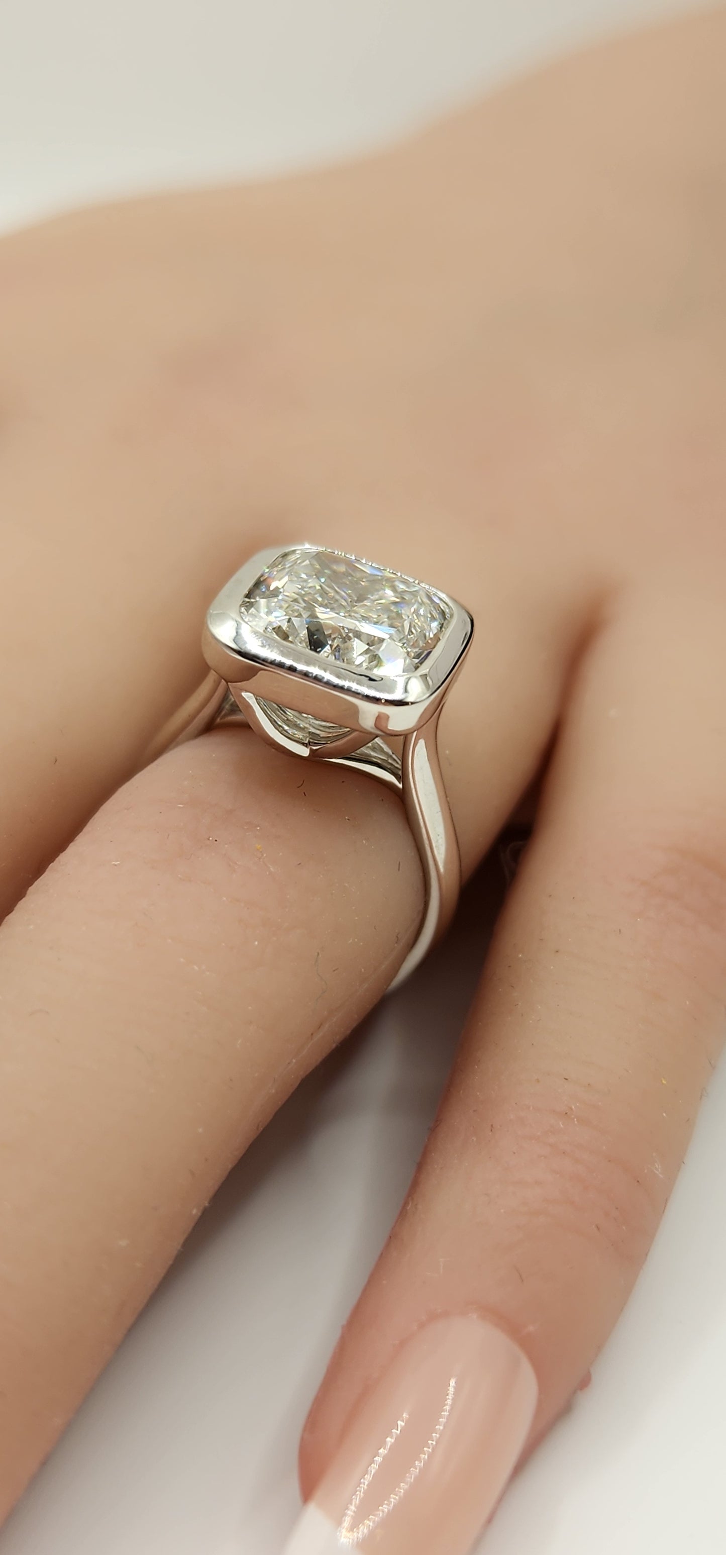 "The Brittney" is a 5.5 Carat Cushion Cut Lab Grown Diamond F/VS1, in a 14k White Gold Full Bezel, Cathedral Setting with Cross Cross Prongs