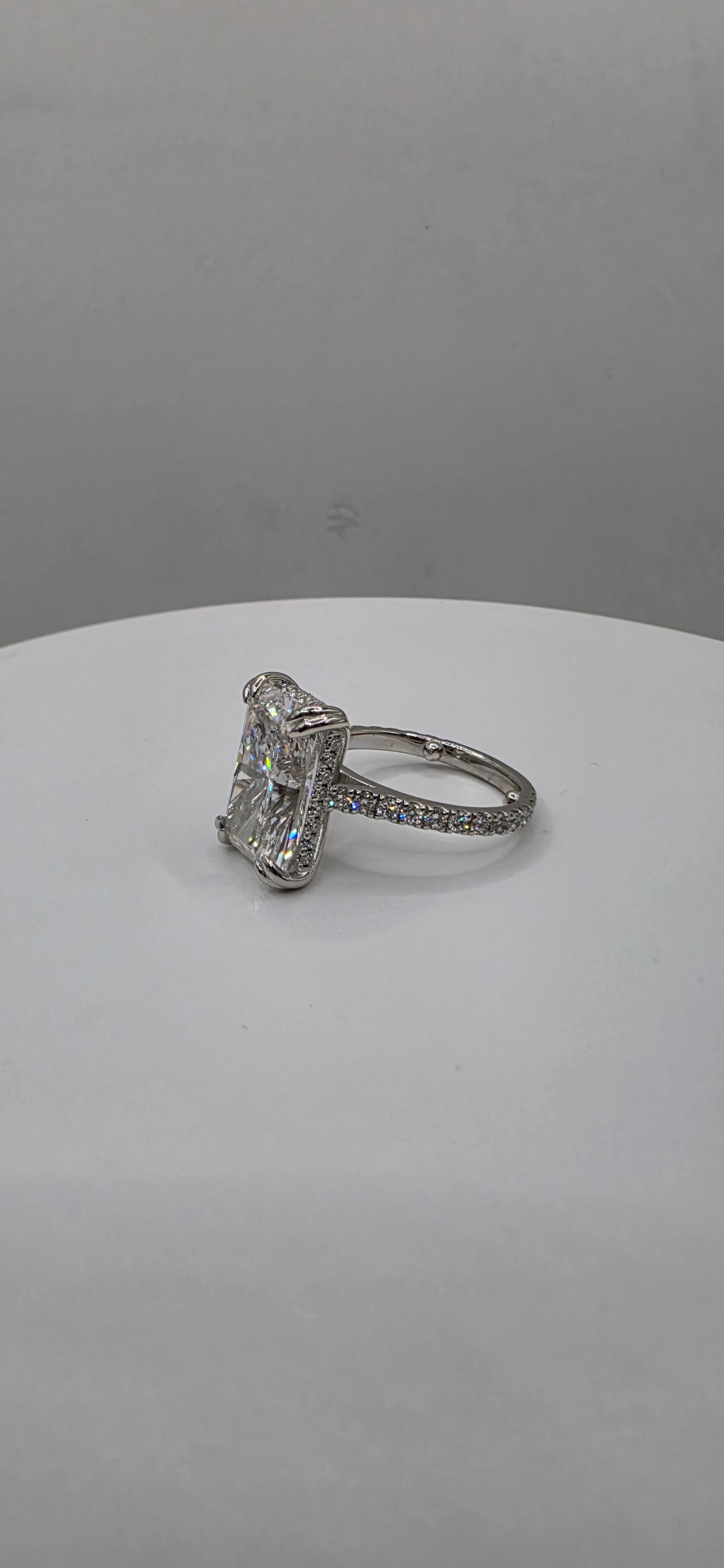 Diamond ring on a white stand against a gray background