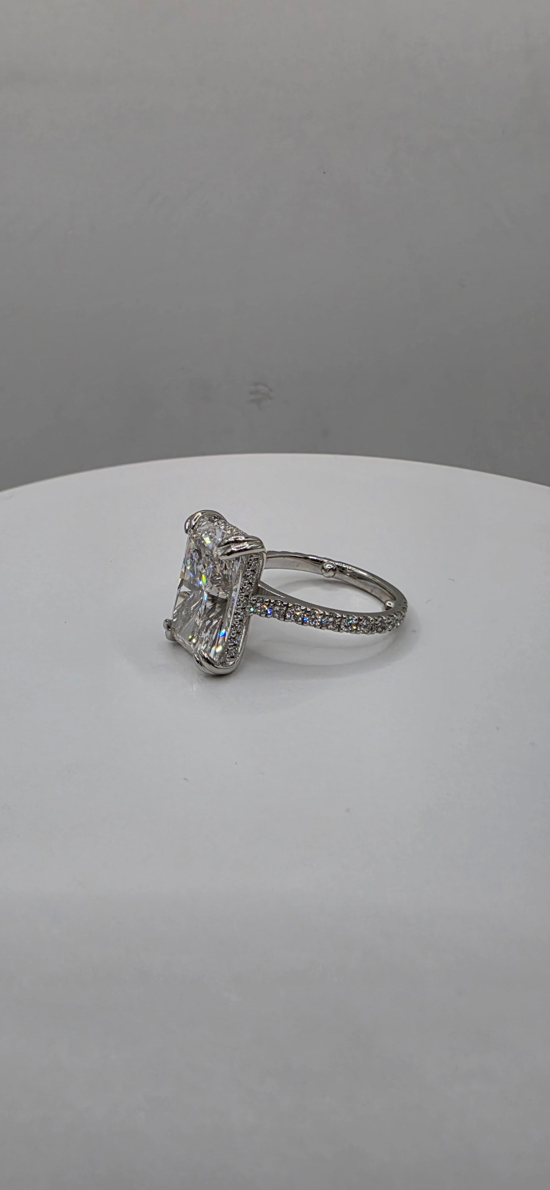 Diamond ring on a white stand against a gray background