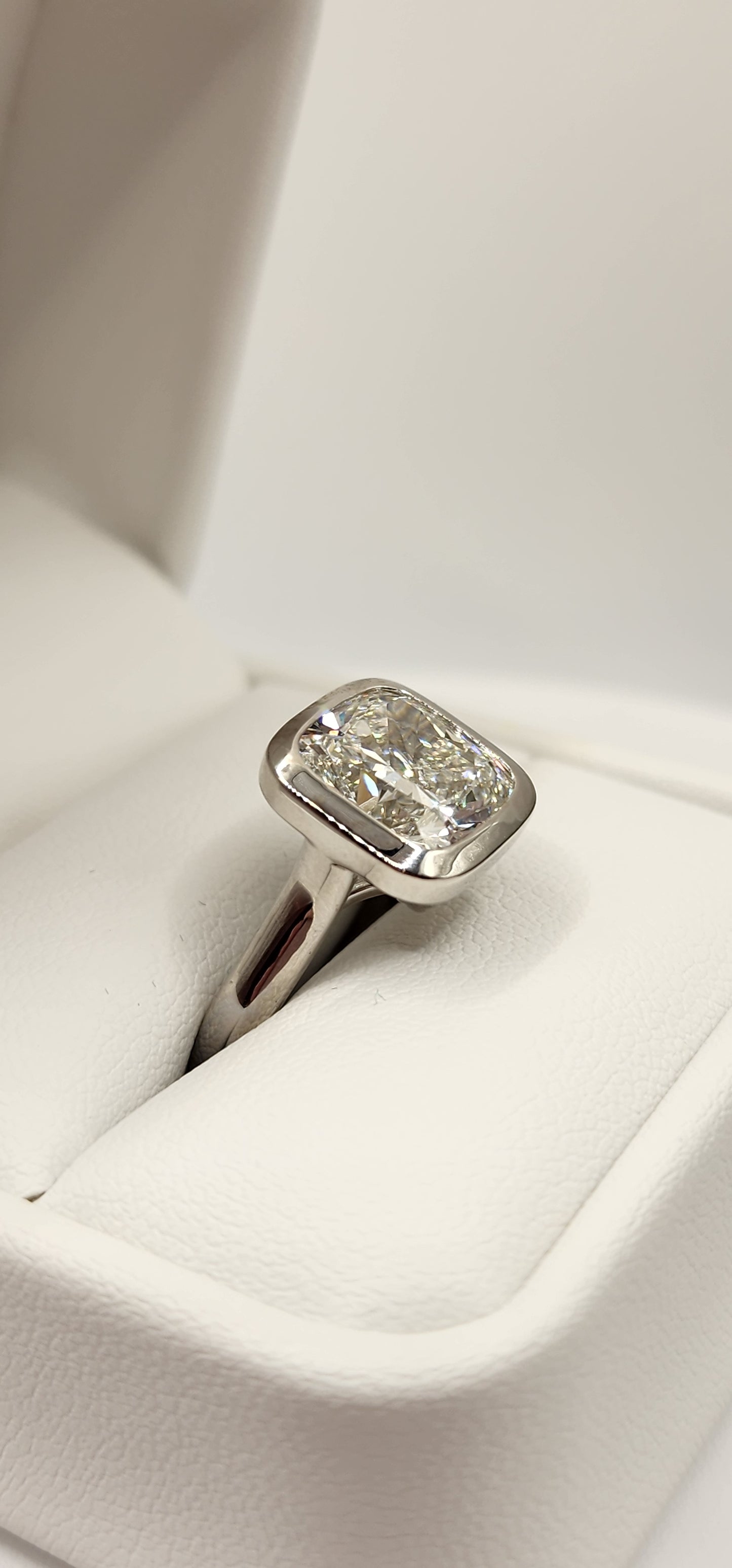 "The Brittney" is a 5.5 Carat Cushion Cut Lab Grown Diamond F/VS1, in a 14k White Gold Full Bezel, Cathedral Setting with Cross Cross Prongs