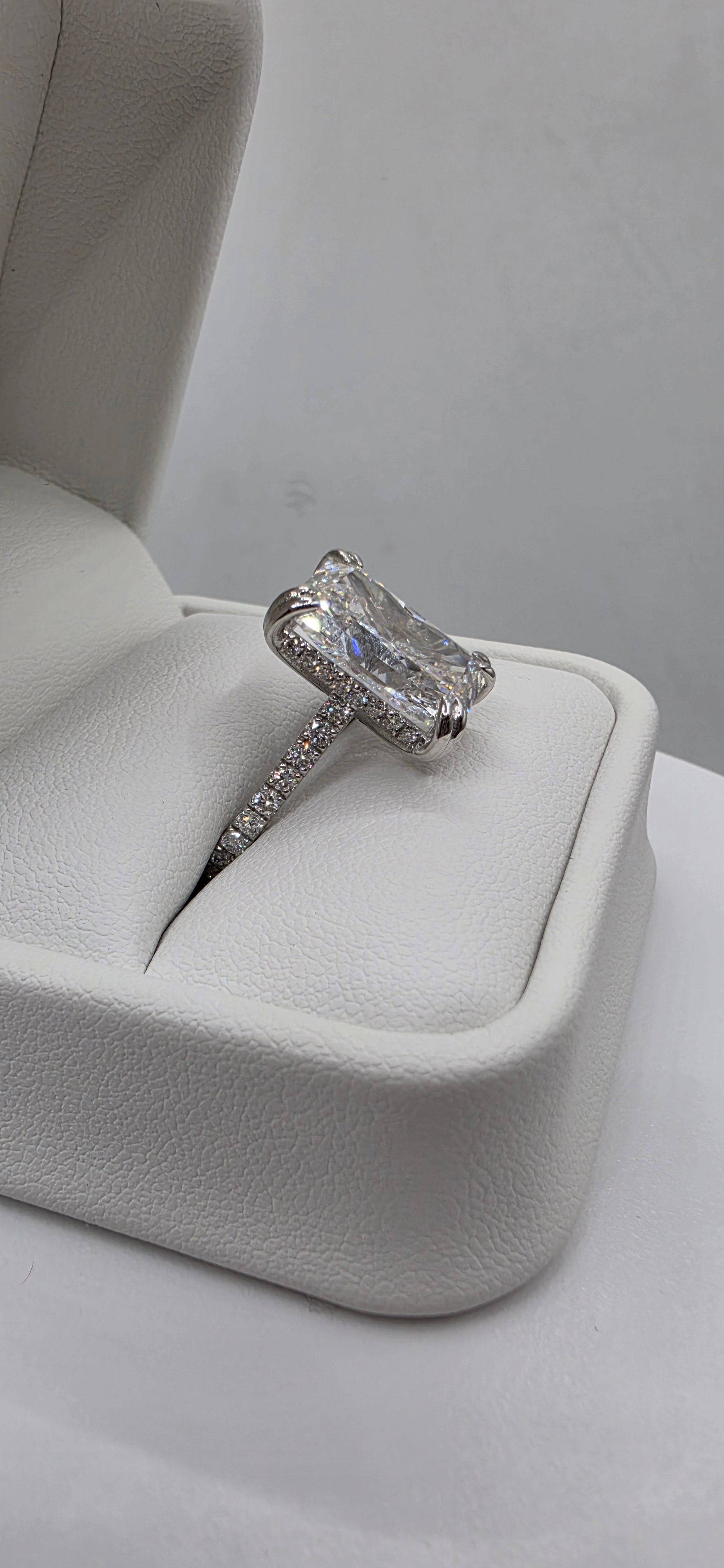 Diamond ring on a white cushioned stand against a neutral background