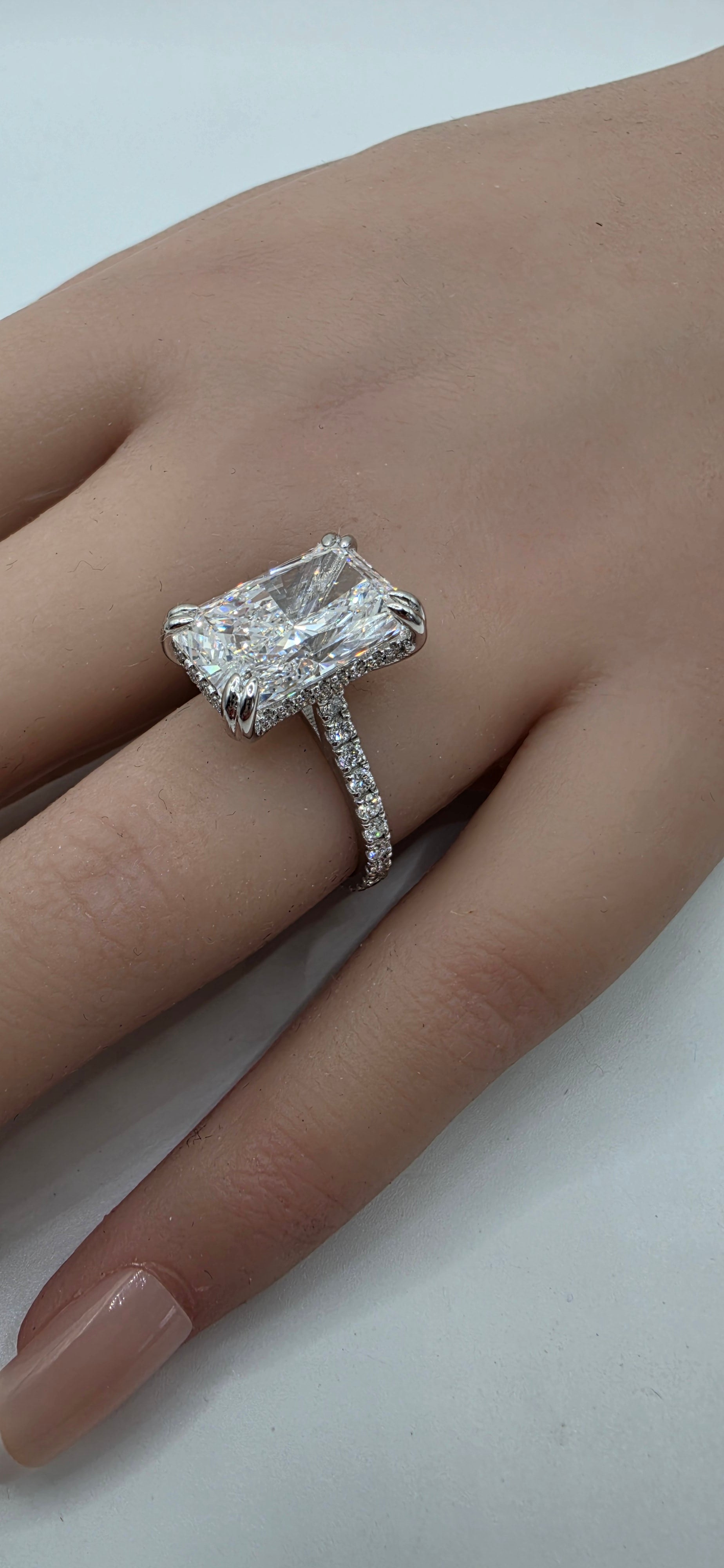 Diamond ring on a finger against a neutral background